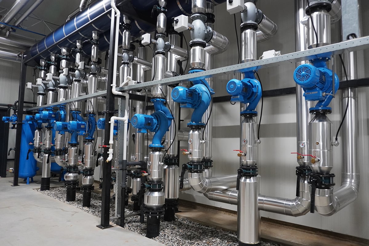 A series of industrial valves and pipes, primarily in shades of blue and grey, installed in a clean and organized fashion. The pipes are connected to various mechanical components, suggesting a system designed for fluid or gas processing.